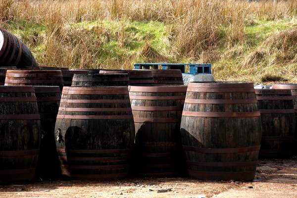 Weathered oak whisky casks outside a distillery warehouse
