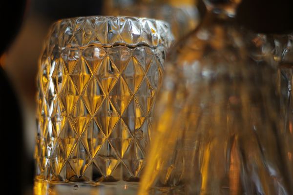 Close-up of a faceted whisky glass catching warm bar light