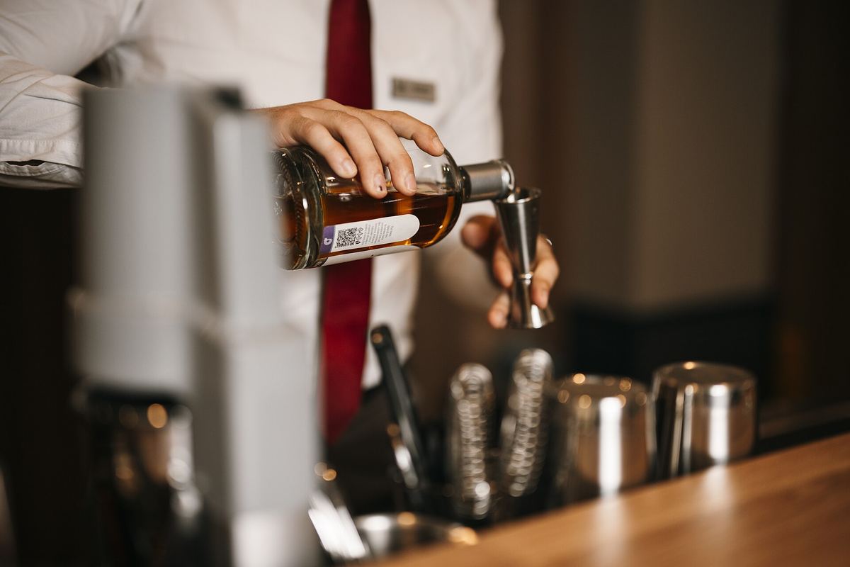 Bartender measuring a single pour of whisky, shown with our alcohol disclaimer on moderation