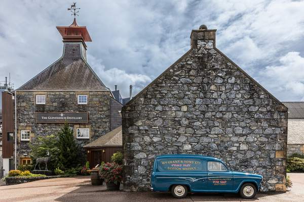 Stone buildings and pagoda roof of Glenfiddich Distillery in Dufftown with a vintage van