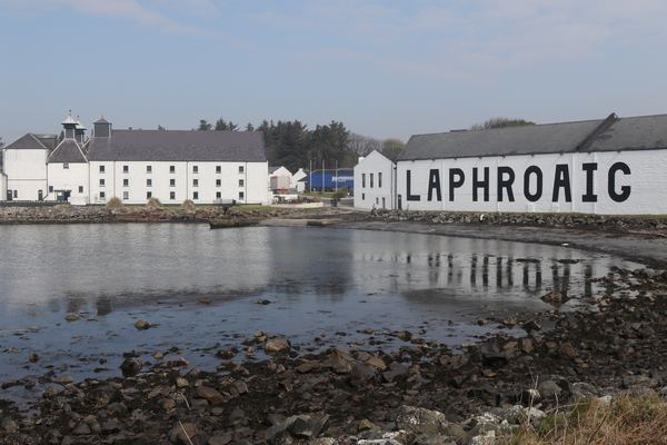 White-washed Laphroaig Distillery with its name painted on the wall above the shore, Islay
