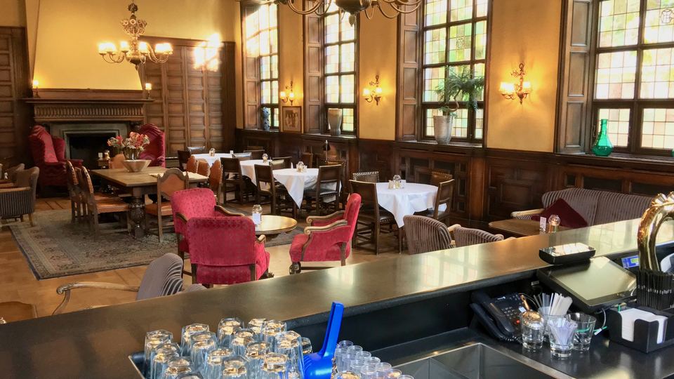Classic wood-panelled whisky bar lounge with chandeliers and armchairs