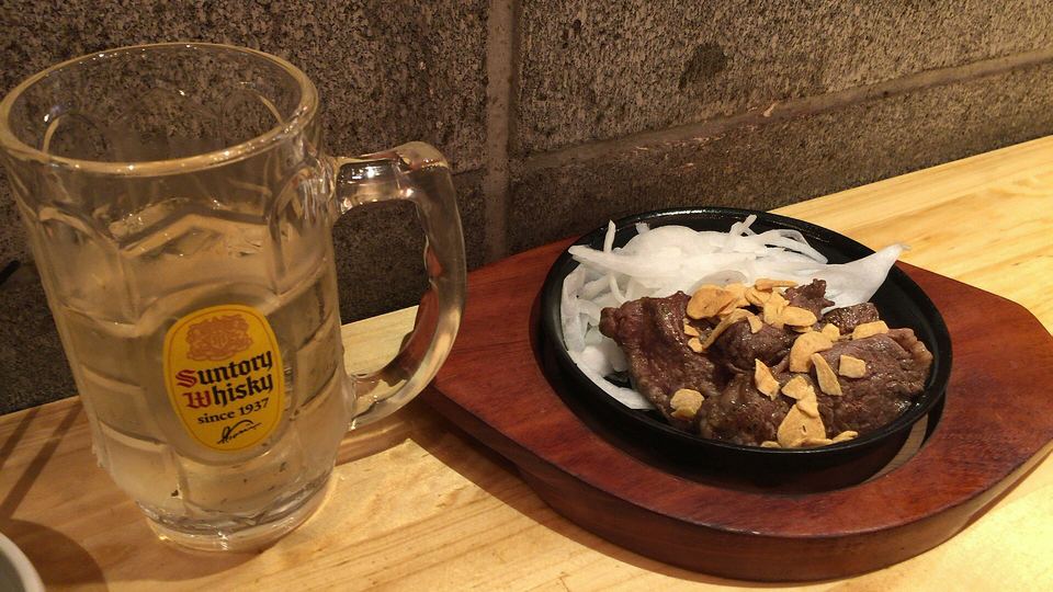 Whisky highball served alongside beef steak and side dishes on a restaurant table