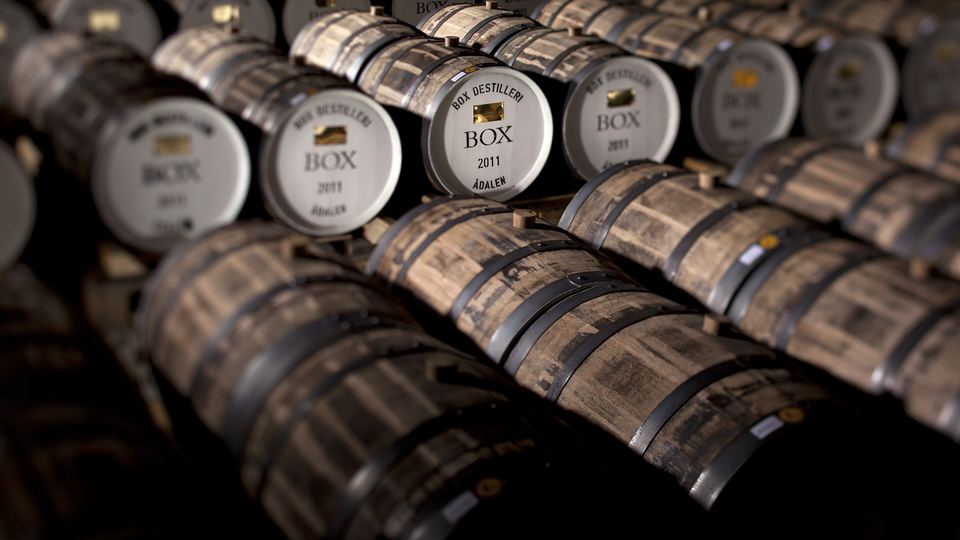 Close-up of whisky cask ends stacked in a dark warehouse